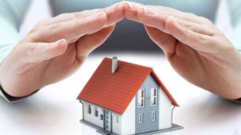 Elleriyle maket bir evin üstünü kapatan kişi